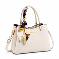 Cream handbag with scarf and charm on white background